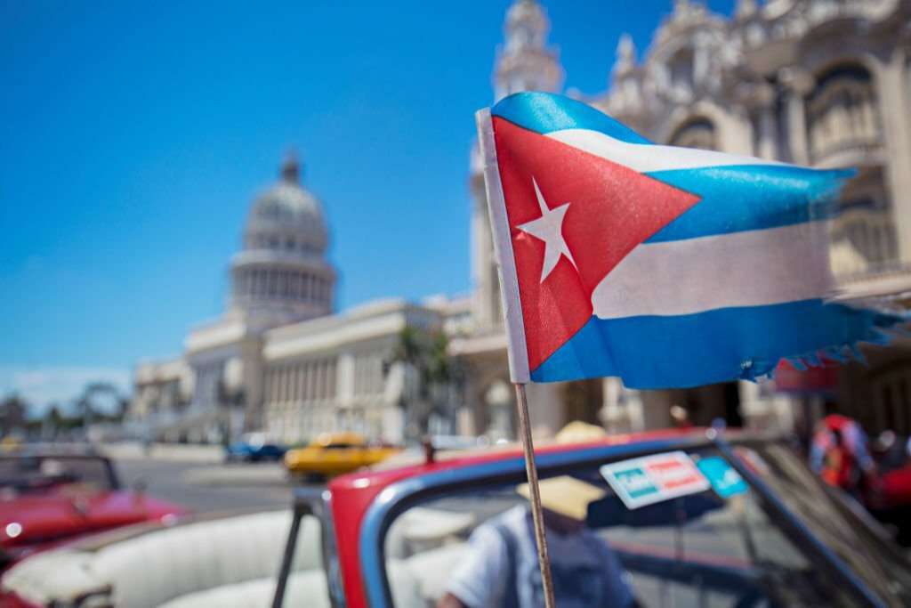 Blurred motion of Cuban flag against Capitolio building in Havana. National flag is in motion against famous parliament building against blue sky.