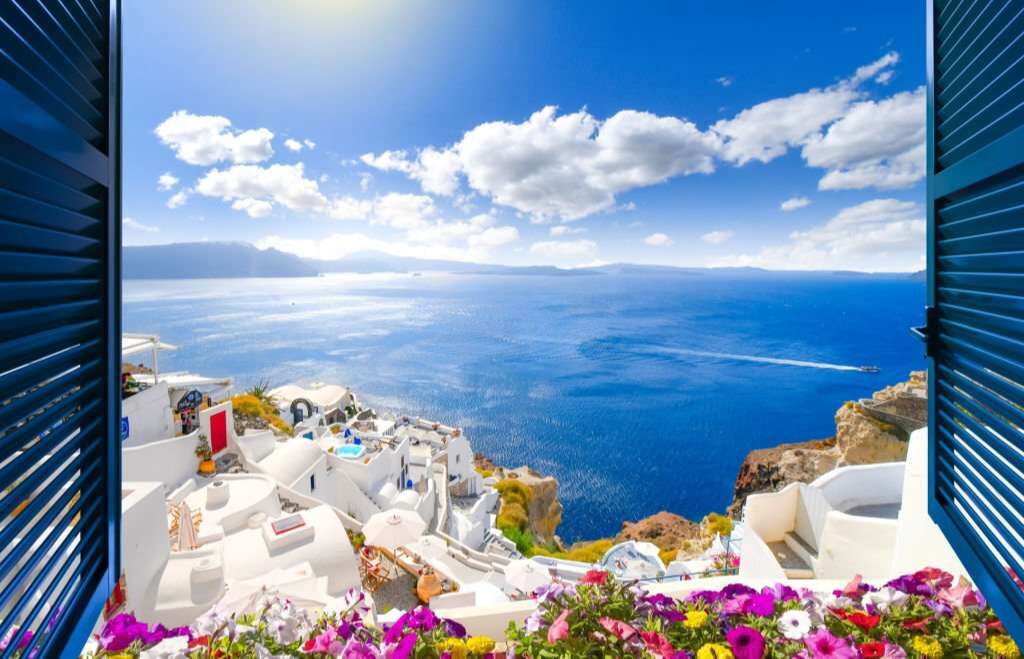 Oia rising above the blue Aegean Sea and the caldera on the island of Santorini, Greece.