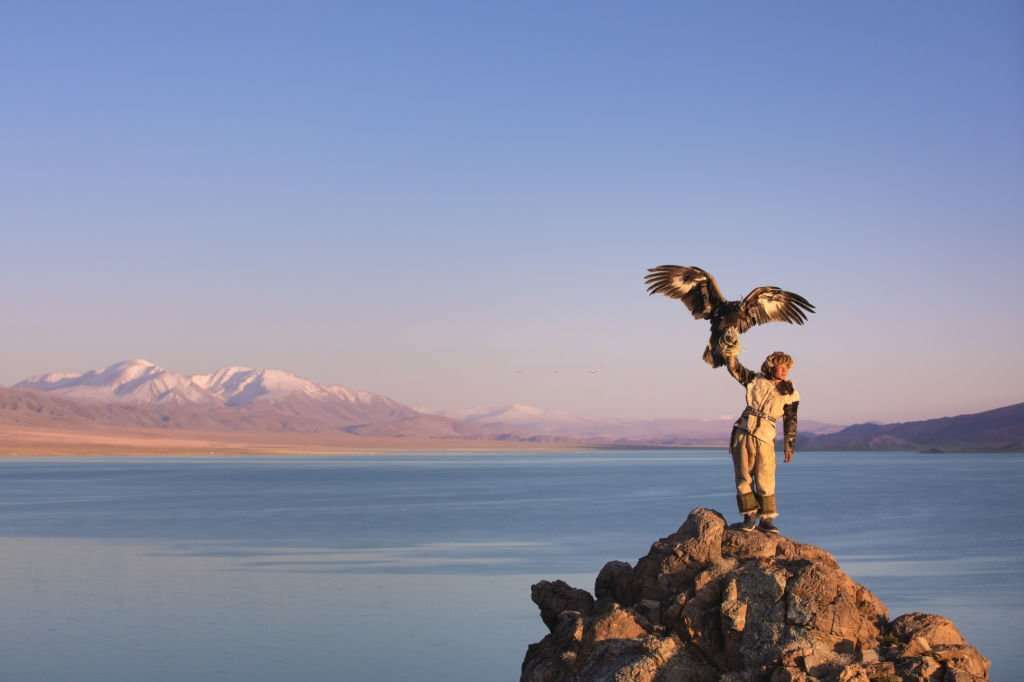 Young kazakh eagle hunter with his golden eagle